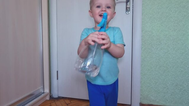 Harmful, laughing child hooligans and splashes water from a spray bottle. Copy space -the concept of play, entertainment, childhood, fun, development of fine motor skills, positive emotions, happiness