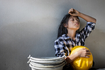 Sad child labor girl relaxing from construction work. World Day Against Child Labour concept.