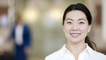 Portrait of attractive Asian female smiling to camera, with space for text