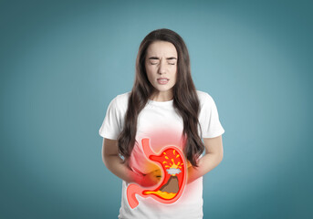 Woman suffering from heartburn on turquoise background. Stomach with erupting volcano symbolizing...