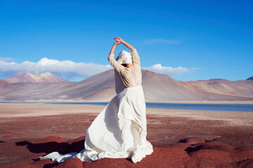 conceptual artistic beauty portrait woman with long dress and face covered with cloth on red stones...