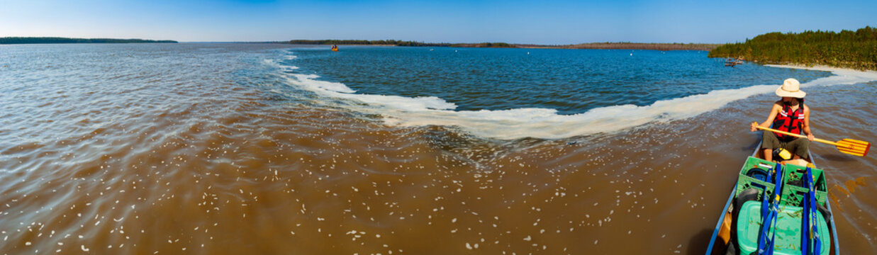 A female paddler looks on as the clearer, warmer waters of the Arkansas River (blue) flow into the colder, turbid Mississippi River (brown) near Arkansas City, Arkansas (panorama)