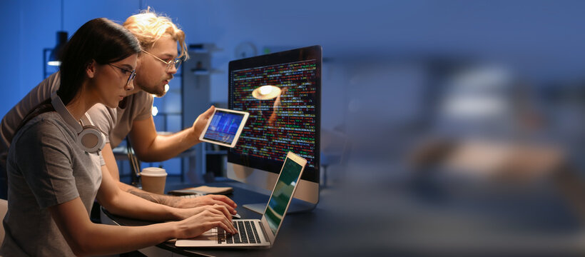 Young programmers working in office at night. Banner for design