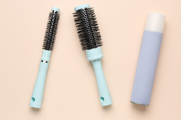 Round brushes with hair spray on beige background