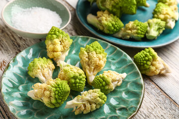 Plate with romanesco cabbage on light wooden background