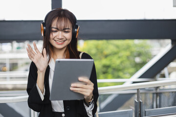 Asian beautiful female video conference calling on digital tablet wear headphones online app. Internet communication. Speak on video while commuting to work. lifestyle communication new generation.