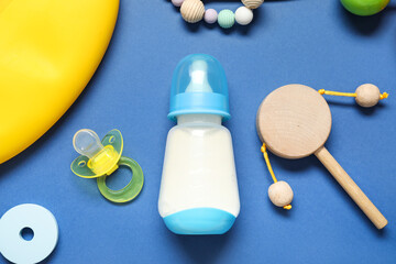 Bottle of milk for baby and accessories on blue background