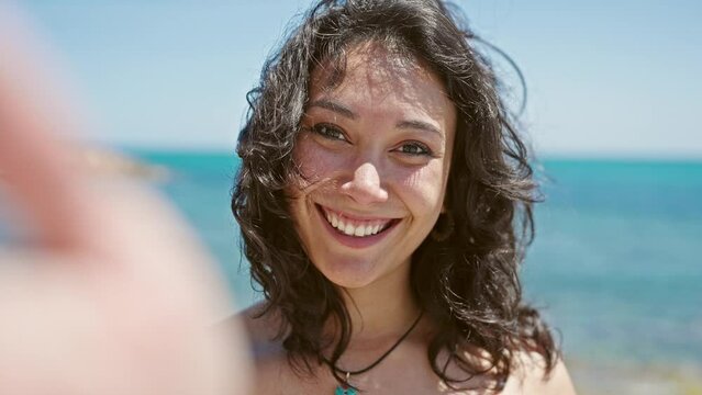Young beautiful hispanic woman tourist smiling confident make selfie by camera kissing at beach
