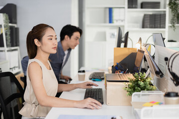 Young asian businesswoman using laptop at office table. company employees sitting at work,...