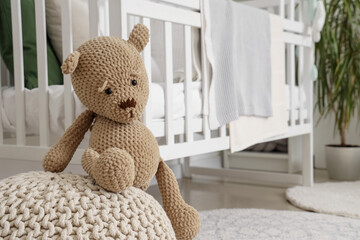 Cute teddy bear on ottoman in children's room