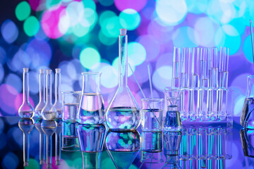 Laboratory investigations. Glass tubes and beakers on blue bokeh background.