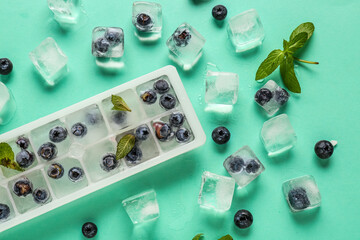 Ice tray with fresh blueberry frozen in ice and mint on blue background