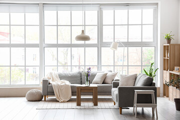 Interior of light living room with grey sofas and big window