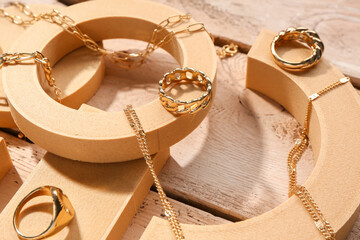 Decorative podiums with golden jewellery on wooden background