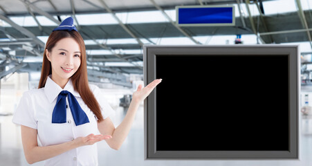 Beautiful Airline stewardess showing the blank TV screen in airport lobby