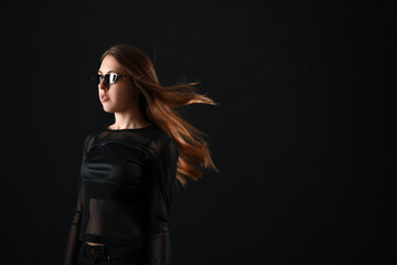 Fototapeta na wymiar Young woman in sunglasses on dark background