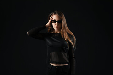 Young woman in sunglasses on dark background