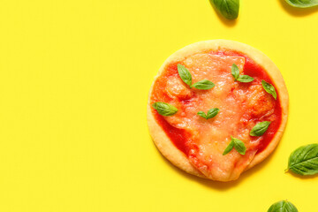 Tasty mini pizza with basil on yellow background