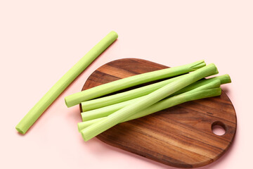 Board with fresh leeks on pink background