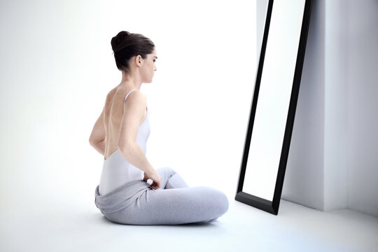 Female Ballerina Stretching By A Mirror In A Studio Before A Dance Class, Performance Or Concert. Art, Creative And Back Of Young Ballet Dancer Doing A Body Warm Up For Classical Dancing In Her Room.