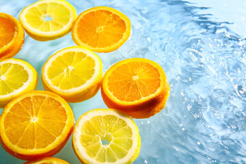 Slices of fresh orange and lemon in water on blue background