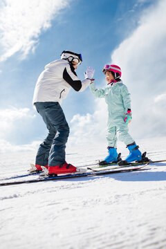 Little girl learning how to ski with her coach