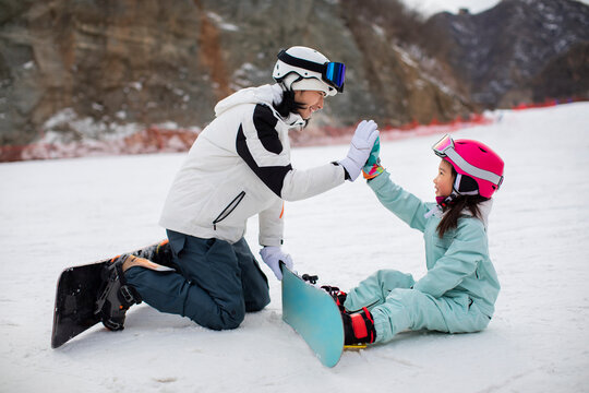 Little girl learning how to snowboard with her coach