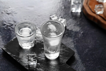 Board with shots of vodka on dark table