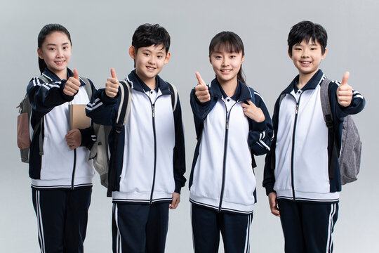 Studio shot of cheerful students doing thumbs-up