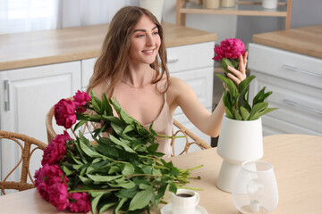 Beautiful young woman with bouquet of peony flowers in kitchen © Pixel-Shot