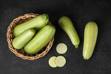 Wicker basket with fresh zucchini on black background