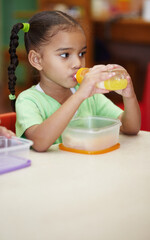 Drink, juice and girl in kindergarten with food for nutrition at school for learning in class . School, drinks and kid at table in classroom with sandwich for an education to learn at creche.