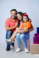 Indian happy family of a father, mother and daughter sitting together on a white background.