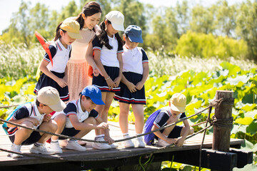 Cheerful school children relaxing in park with their teacher