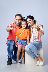 Obraz premium Indian happy family of a father, mother and daughter sitting together on a white background.