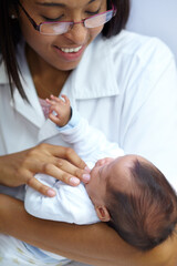 Healthcare, smile and a pediatrician with a baby in the hospital for insurance, care or treatment. Medical, children and a happy doctor woman in glasses holding a newborn infant in a health clinic