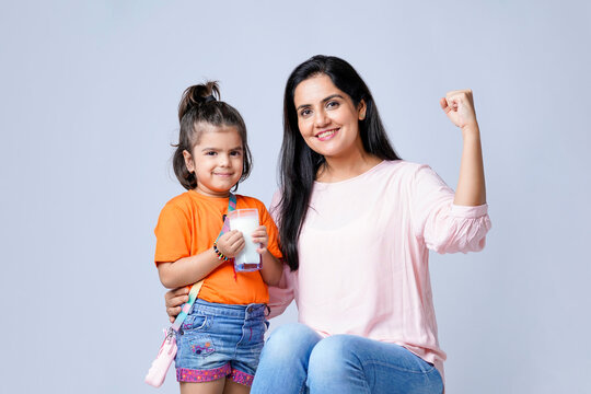 Indian mother giving milk in glass his daughter on white background.