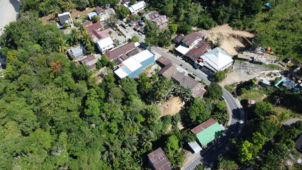 An impressive aerial view of a winding asphalt road with numerous houses and trees around it. The bird's-eye view offers a unique perspective on the surrounding environment.