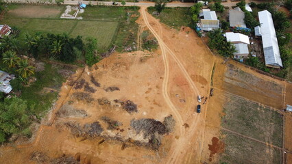 A stunning aerial view of land clearing where the brown soil contrasts with the green trees surrounding it. The sight captures the beauty and destruction of human activity on the environment.