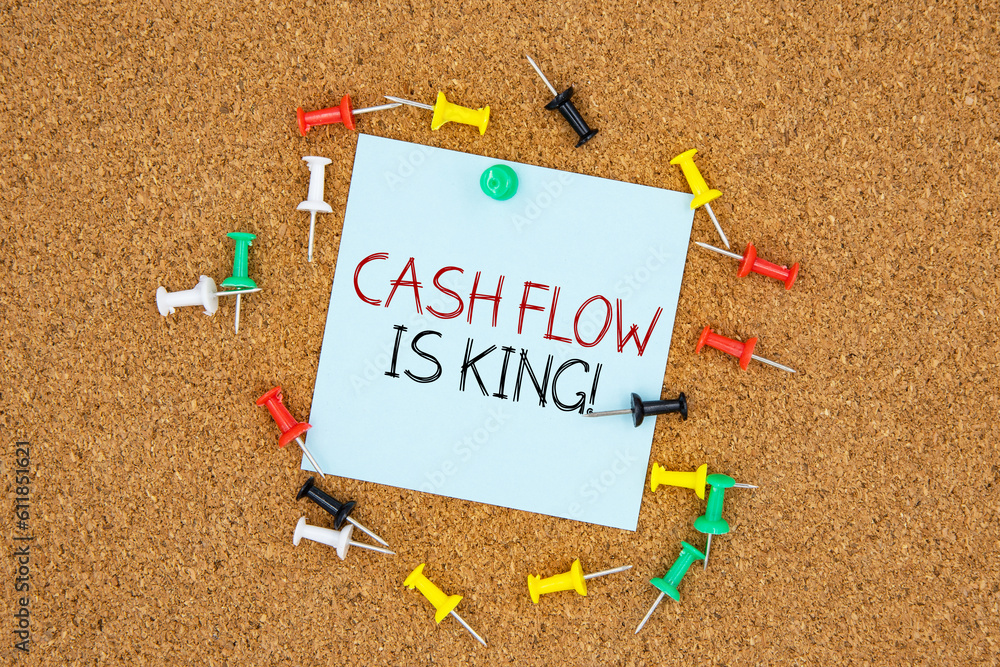 Poster cash flow is king text on light blue post-it paper pinned on bulletin cork board surrounding by mult