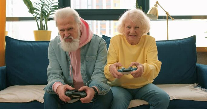 old happy grandmother is winning grandfather celebrating victory while playinbg computer game, victory success luck Slow motion game battle together retirement Leisure time and people