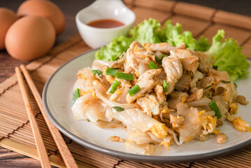 Stir fired rice noodle with chicken and egg that is Thai street food and tasty food, serve with chili sauce
