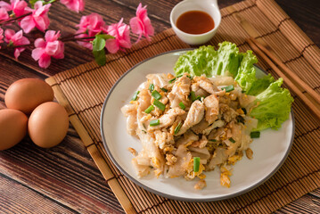 Stir fired rice noodle with chicken and egg that is Thai street food and tasty food, serve with chili sauce