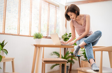 Portrait young beautiful asian creative woman relax sit on desk use computer laptop. Smile happy asian girl drink coffee at table home. Freelance small business asian owner sme work from home concept