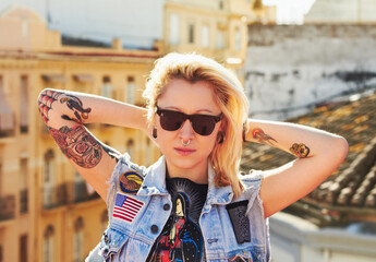 Tattoo, portrait and fashion woman with sunglasses in city, urban body art and stylish outdoor....