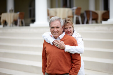 Hug, portrait and an old couple on hotel steps for travel, vacation or tourism in luxury...