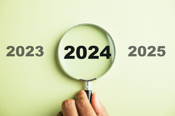 A magnifier zooming in on the 2024 icon, the target business for the upcoming year. It represents...