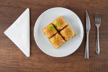 Turkish baklava with pistachio in plate.A plate baklava on wooden background,top view 