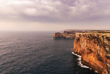 Fototapeta na wymiar Cliffs at Cabo de San Vicente,with the Stone of the Seagulls in the background,Sagres,Portugal.