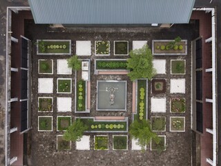 Captured using a drone, the view from above reveals an aesthetically pleasing layout of a garden that resembles a maze with square-shaped patterns.